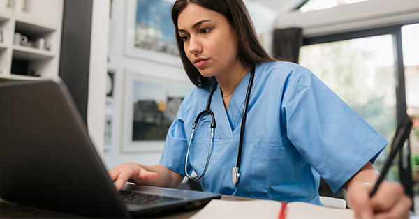 healthcare professional works on laptop