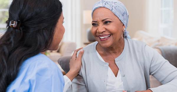 healthcare professional talks to elderly cancer patient